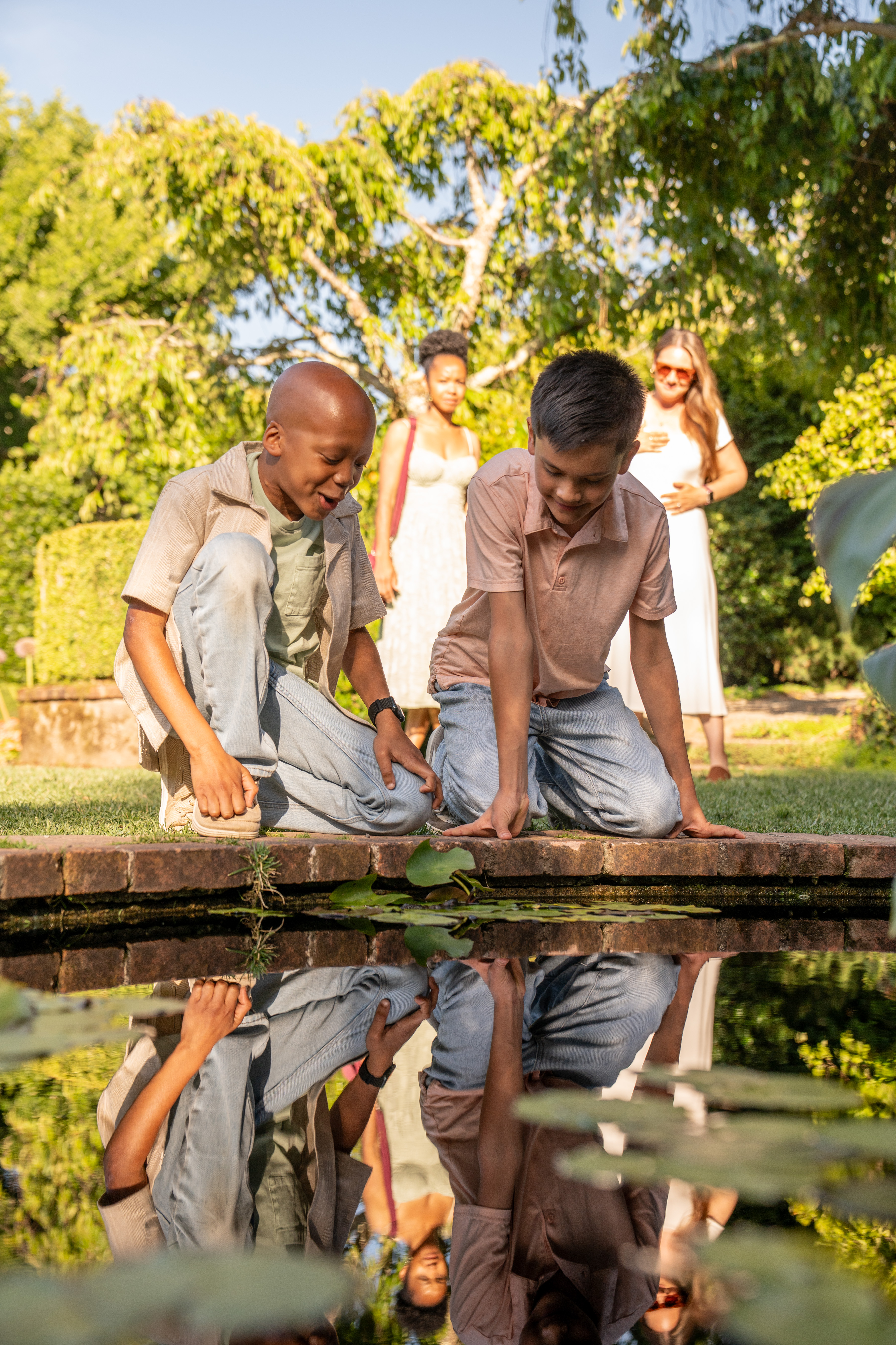 Ian and a kid looking into a pond as their mothers look on